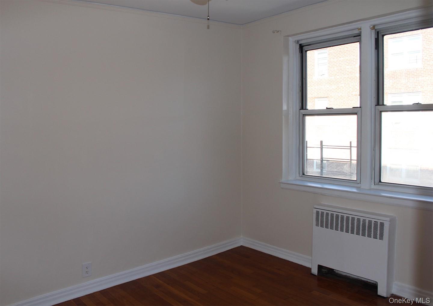 811 Bronx River Road, Unit 5A Yonkers, NY 10708 - Photo 10 of 18 Empty room with radiator, dark wood-style floors, and crown molding