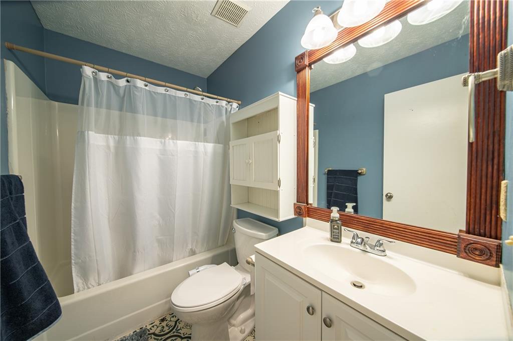 143 Lee Road 979 Phenix City, AL 36870 - Photo 27 of 37 Full bathroom with vanity, toilet, a textured ceiling, and shower / tub combo with curtain