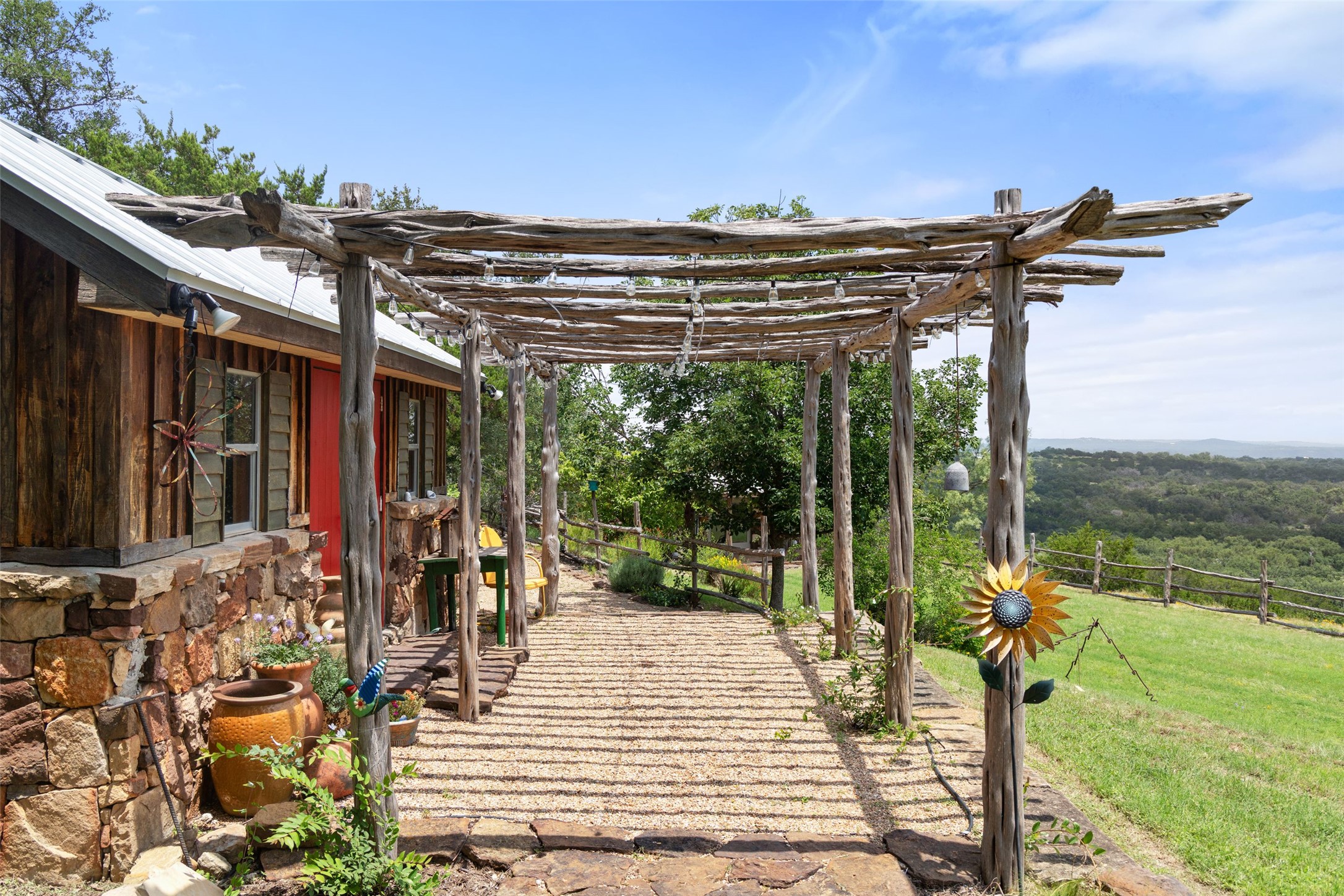 8400 Ranch Road 1431 Marble Falls, TX 78654 - Photo 15 of 30 Rustic wood pergola offers a charming entryway to a stone and timber-clad home with sweeping hill country views.