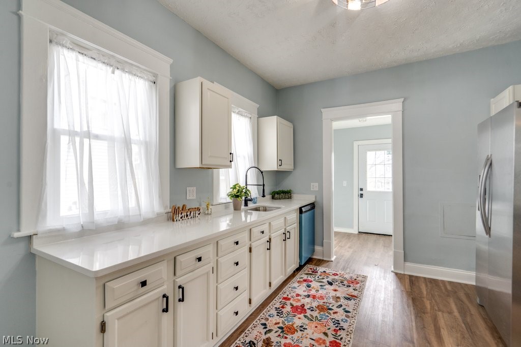 12 South 4th Street Rittman, OH 44270 - Photo 13 of 48 Kitchen with stainless steel appliances, white cabinetry, dark wood-type flooring, light stone counters, and a textured ceiling