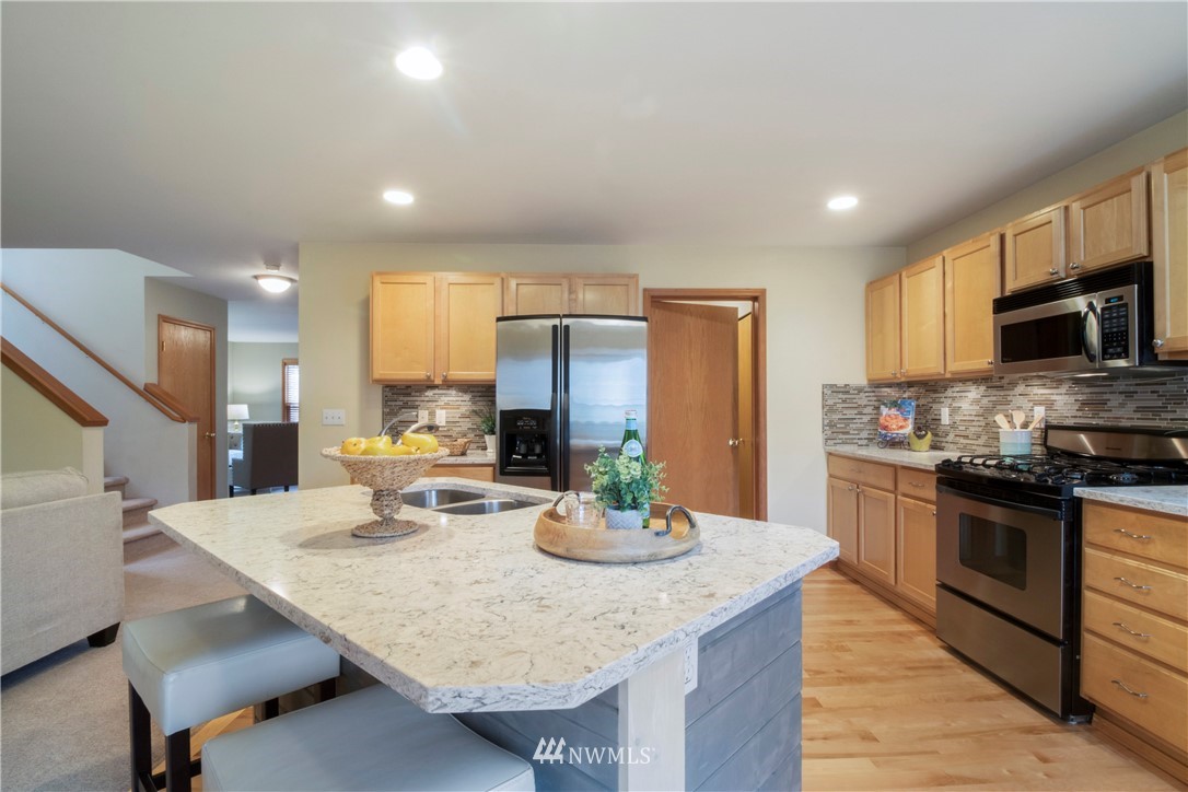 34829 Southeast Ridge Street Snoqualmie, WA 98065 - Photo 2 of 19 a kitchen with stainless steel appliances kitchen island granite countertop a table chairs sink and cabinets