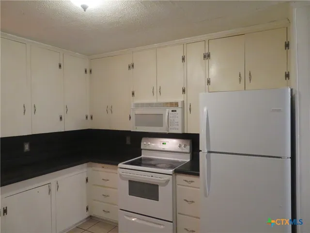 a kitchen with a refrigerator stove and white cabinets