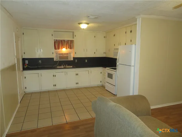 a kitchen with granite countertop a sink a stove and cabinets