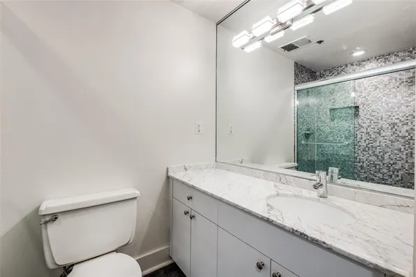 a bathroom with a granite countertop sink a toilet and a mirror