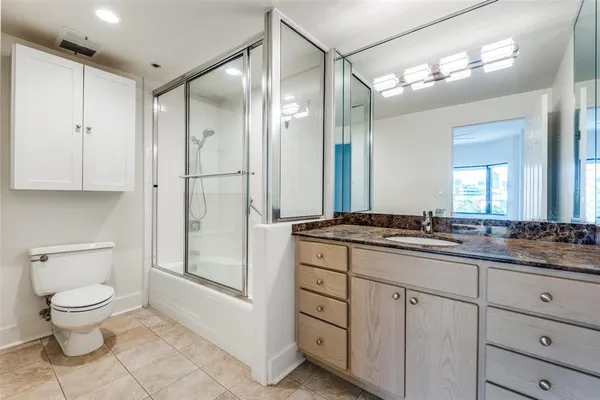 a bathroom with a granite countertop sink a toilet and a mirror