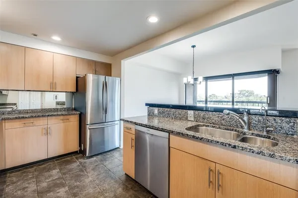 a kitchen with granite countertop kitchen island stainless steel appliances a sink and a refrigerator