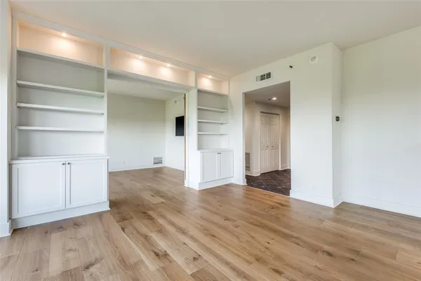 a view of an empty room with wooden floor and closet