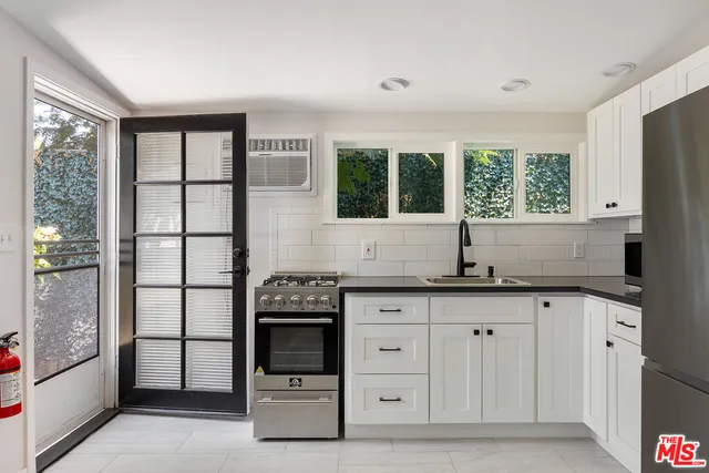 a kitchen with granite countertop a stove a sink and a refrigerator
