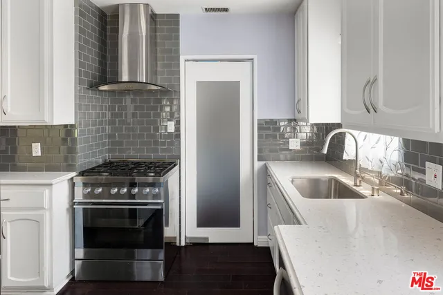 a kitchen with granite countertop a sink stove and cabinets