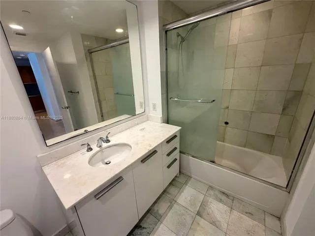 a bathroom with a sink a toilet a mirror and shower