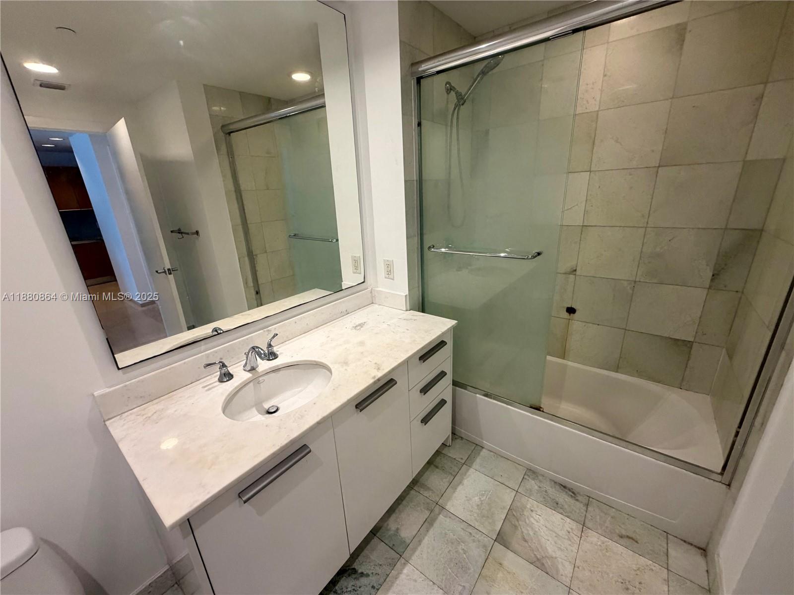 1050 Brickell Avenue, Unit 2206 Miami, FL 33131 - Photo 4 of 9 a bathroom with a sink a toilet a mirror and shower