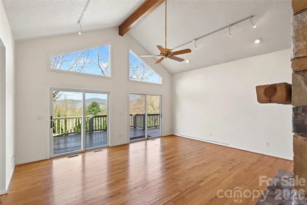a view of an empty room with a window and wooden floor