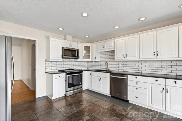 a kitchen with granite countertop white cabinets and stainless steel appliances