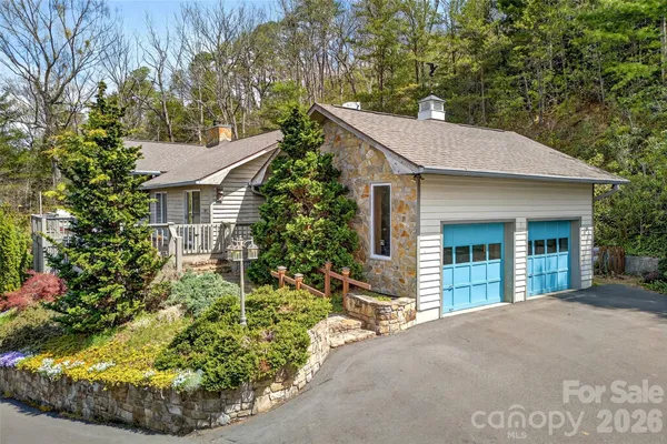 a view of a house with a small yard plants and large tree