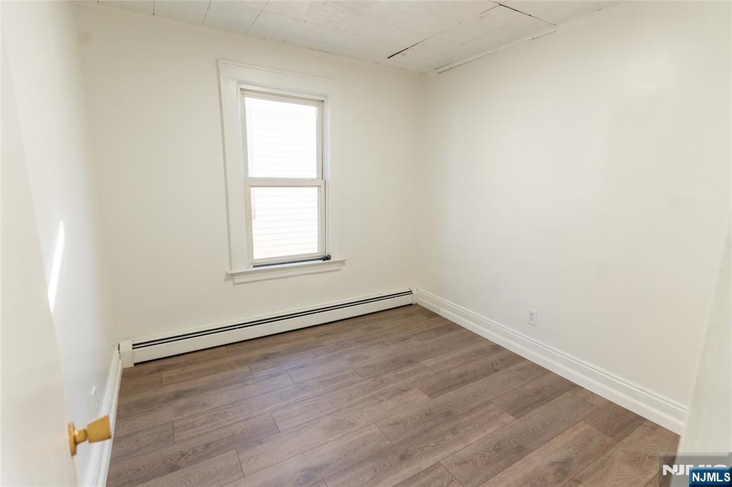 125 Clark Place, Unit 123 Elizabeth, NJ 07206 - Photo 8 of 16 an empty room with wooden floor and windows