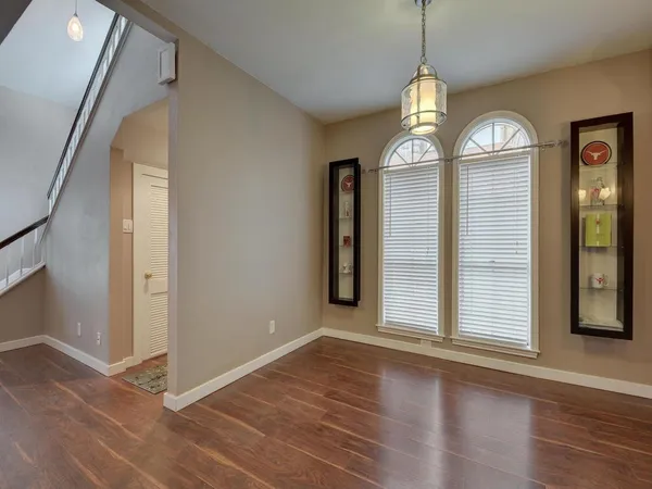 a view of a room with wooden floor chandelier and windows