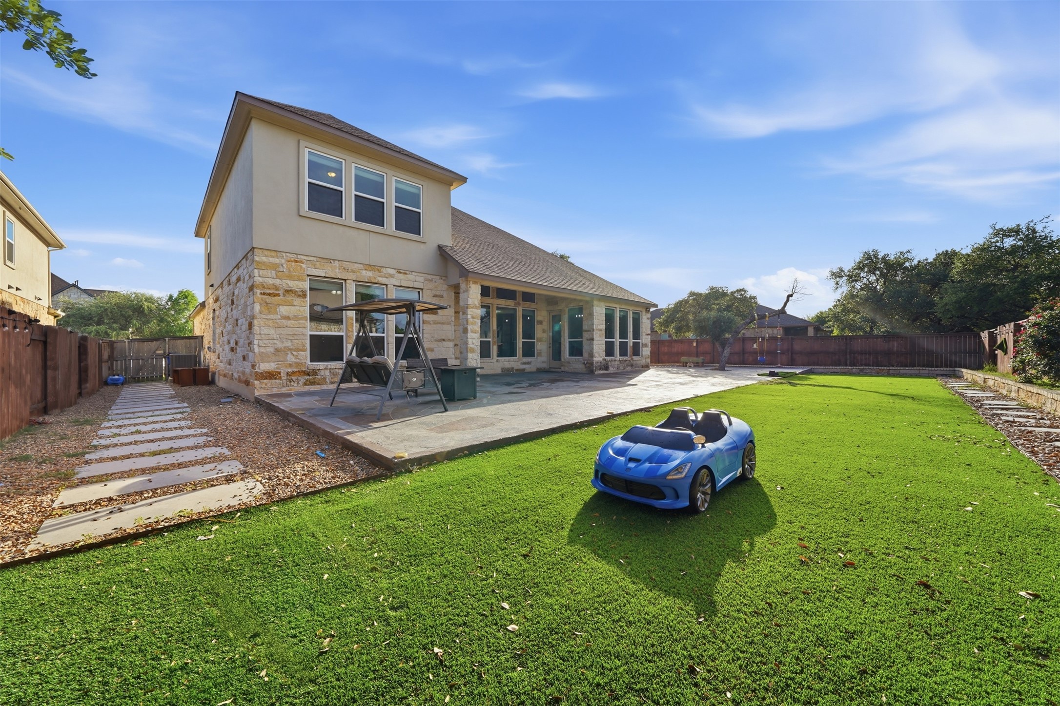 4301 Logan Ridge Drive Cedar Park, TX 78613 - Photo 36 of 38 Back of property with stone siding, a fenced backyard, a patio area, and stucco siding