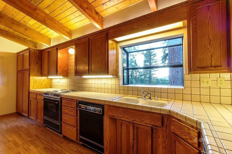 25020 Rim Rock Road Idyllwild, CA 92549 - Photo 15 of 34 a view of a kitchen with a sink and wooden cabinets