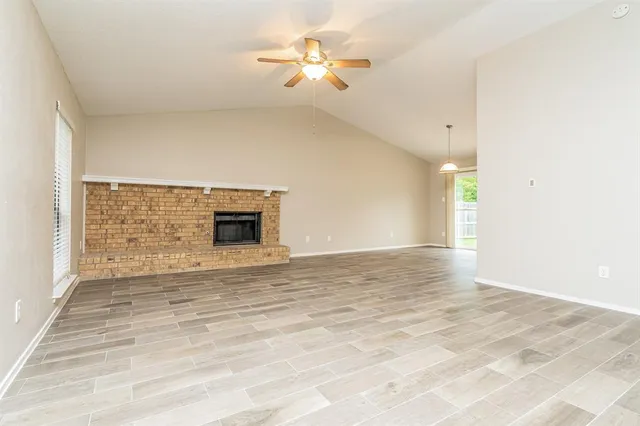 a view of an empty room with chandelier fan and wooden floor