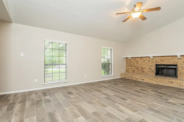 wooden floor fireplace and windows in an empty room