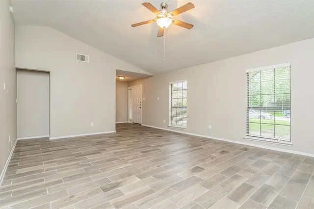 a view of an empty room with a window and a chandelier fan