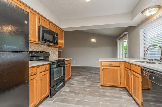 a large kitchen with stainless steel appliances granite countertop a stove top oven a sink dishwasher a dining table and chairs with wooden floor