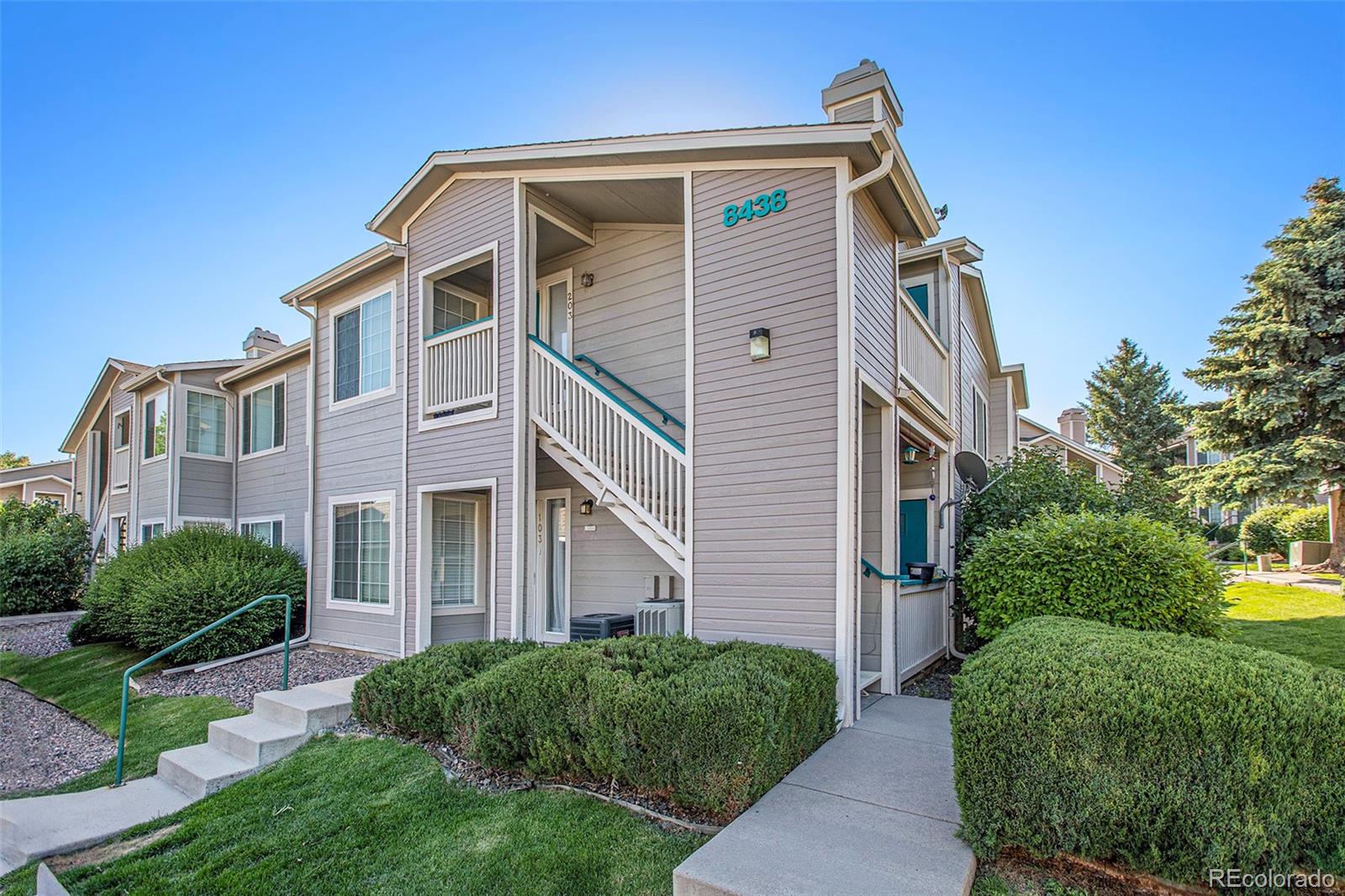 8438 South Thunder Ridge Way, Unit 102 Highlands Ranch, CO 80126 - Photo 11 of 16 a view of a blue house with a yard and plants