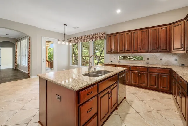 a kitchen with stainless steel appliances granite countertop a sink a stove and a wooden cabinets