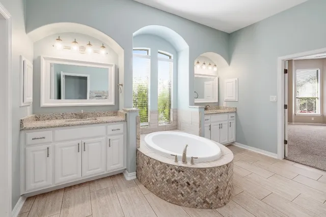 a spacious bathroom with a granite countertop sink mirror and bathtub