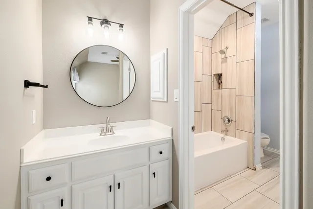 a bathroom with a tub sink double vanity and mirror