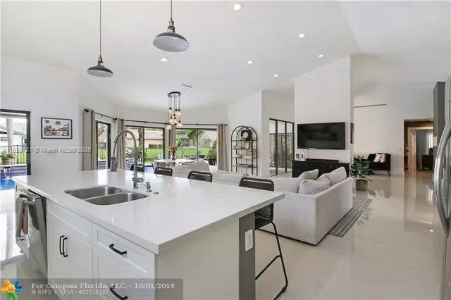 a view of living room kitchen with stainless steel appliances granite countertop a stove and a sink
