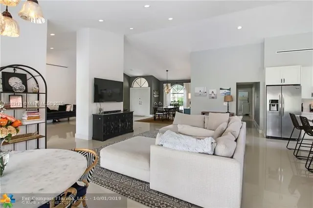 a living room with furniture a flat screen tv and kitchen view