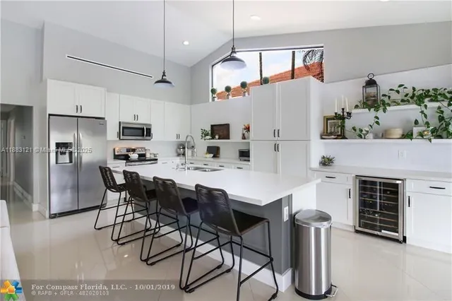 a kitchen with stainless steel appliances kitchen island granite countertop a table chairs and a refrigerator