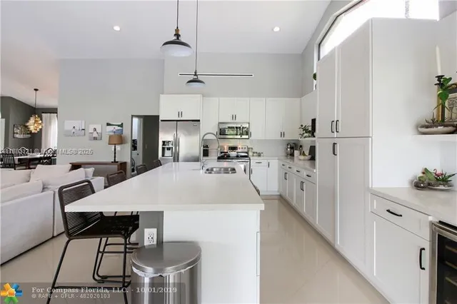 a kitchen with stainless steel appliances kitchen island a table chairs refrigerator and sink