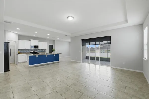 a living room with stainless steel appliances kitchen island granite countertop a refrigerator and a sink