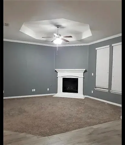 an empty room with a fireplace and chandelier fan