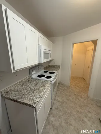 a kitchen with granite countertop a sink stove and refrigerator