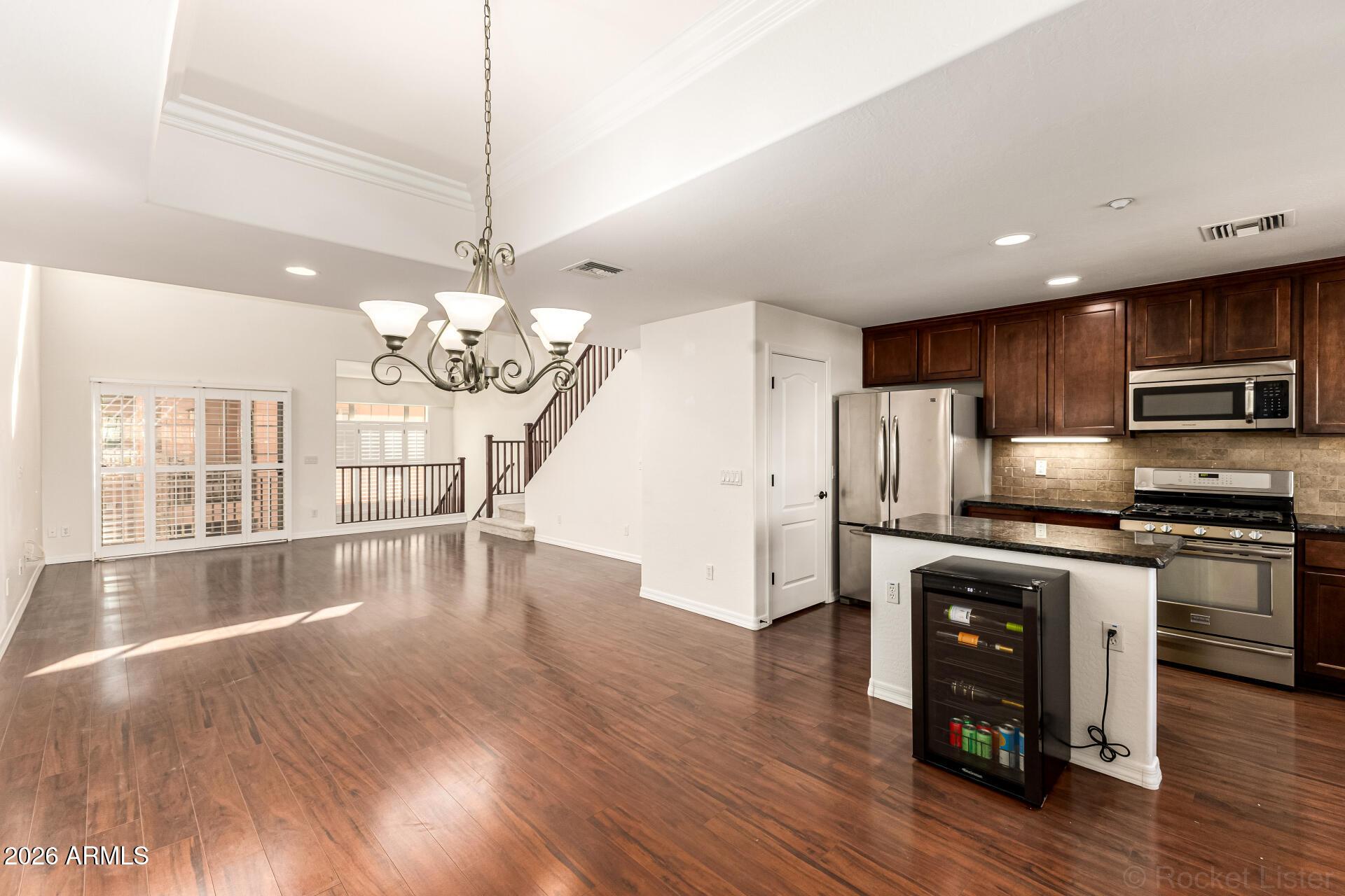 6940 East Cochise Road, Unit 1043 Paradise Valley, AZ 85253 - Photo 11 of 35 a kitchen with stainless steel appliances granite countertop a refrigerator a stove top oven a sink dishwasher a dining table and chairs with wooden floor