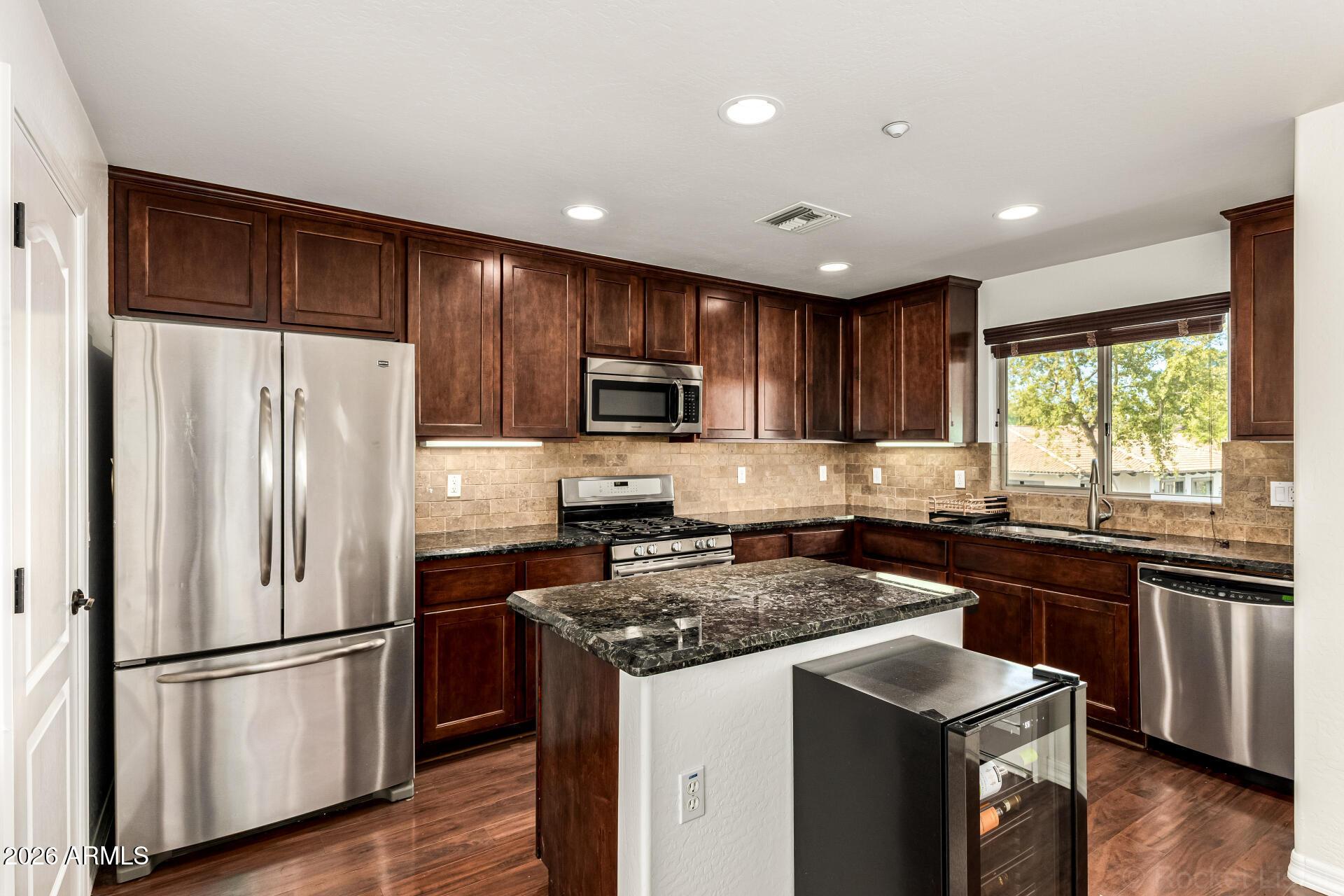 6940 East Cochise Road, Unit 1043 Paradise Valley, AZ 85253 - Photo 12 of 35 a kitchen with wooden cabinets and stainless steel appliances