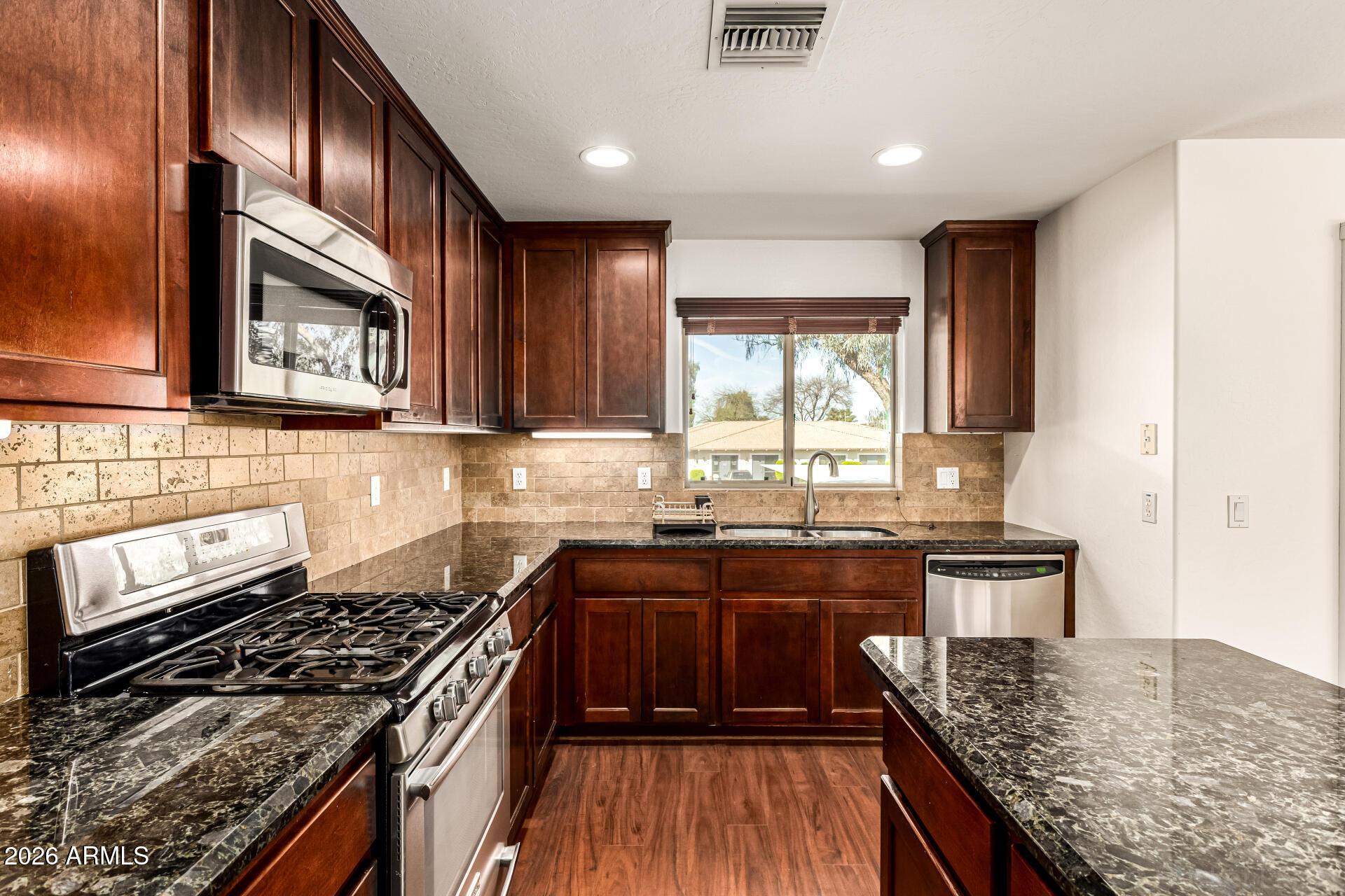 6940 East Cochise Road, Unit 1043 Paradise Valley, AZ 85253 - Photo 13 of 35 a kitchen with stainless steel appliances granite countertop wooden cabinets stove top oven and sink