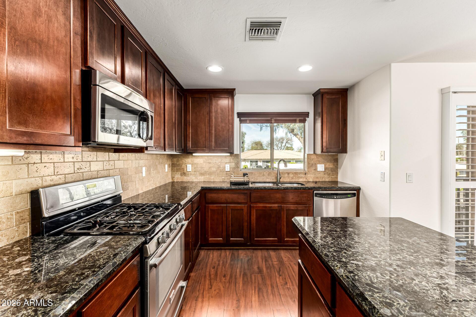 6940 East Cochise Road, Unit 1043 Paradise Valley, AZ 85253 - Photo 16 of 35 a kitchen with stainless steel appliances granite countertop wooden cabinets stove top oven and sink