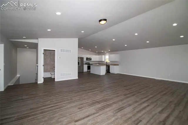 a large kitchen with kitchen island a sink a stove a refrigerator and white cabinets with wooden floor