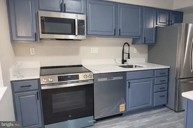 a kitchen with cabinets stainless steel appliances and a wooden floor