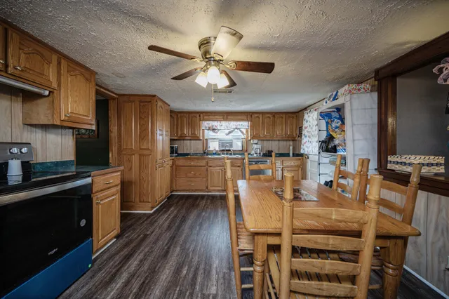 a kitchen with stainless steel appliances kitchen island granite countertop a refrigerator a stove top oven a sink with island and chairs