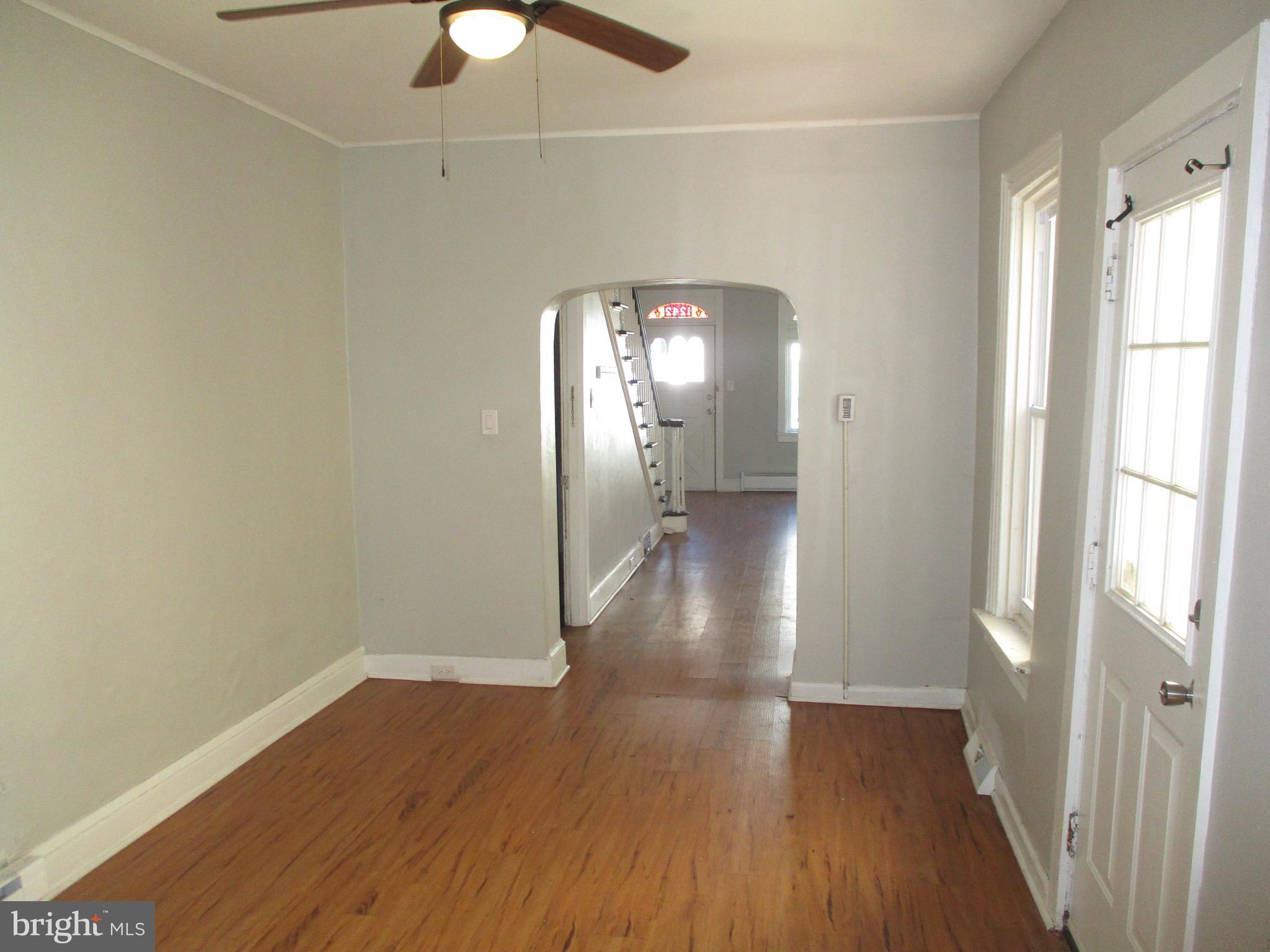 1242 Muhlenberg Street Reading, PA 19602 - Photo 5 of 18 a view of a room with wooden floor a ceiling fan and windows