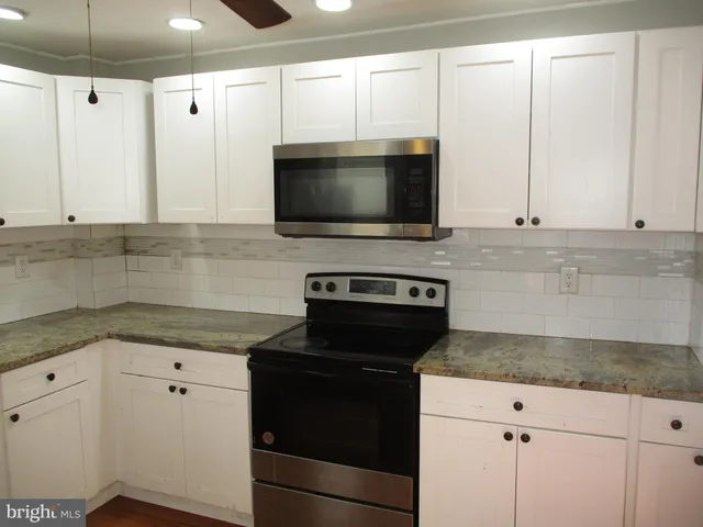 a kitchen with granite countertop white cabinets and black appliances