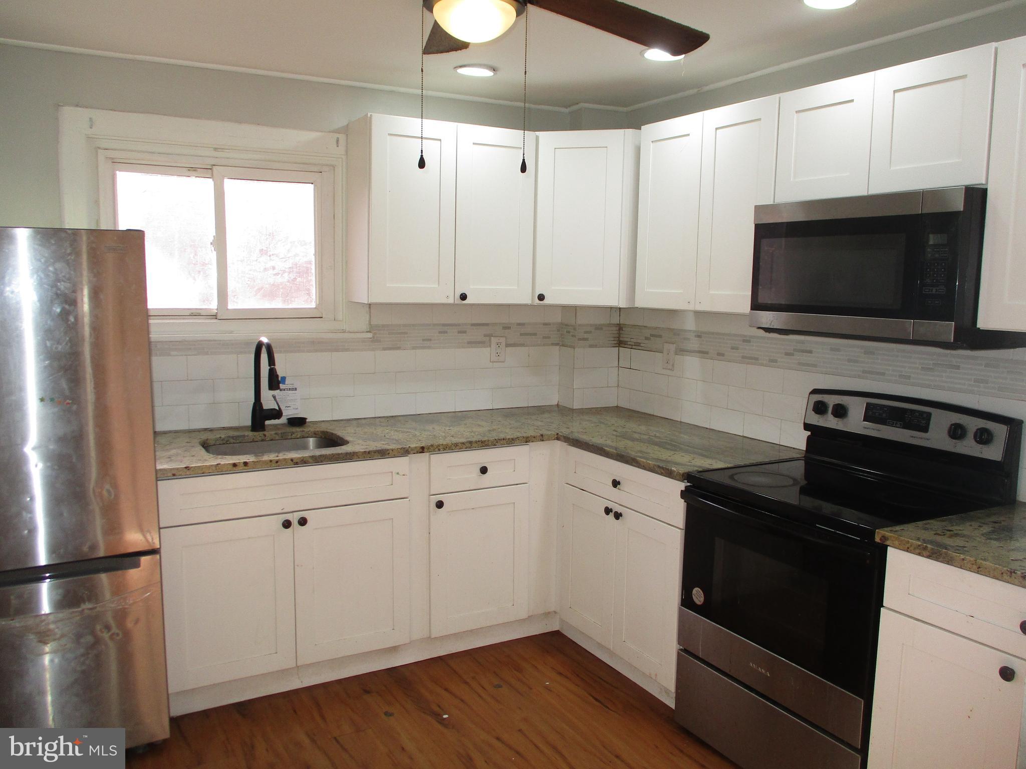 1242 Muhlenberg Street Reading, PA 19602 - Photo 7 of 18 a kitchen with granite countertop white cabinets white stainless steel appliances and sink