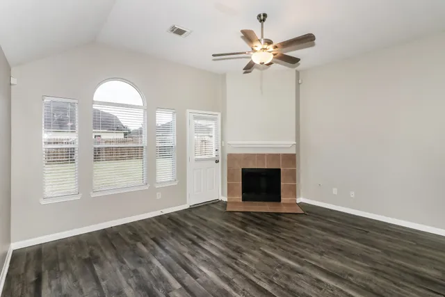 a view of an empty room with wooden floor fireplace and a window