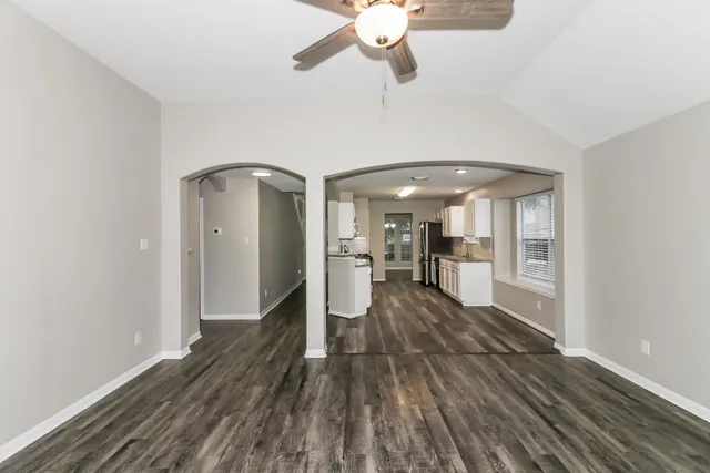a view of a room with wooden floor stairs and a kitchen space