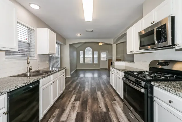 a kitchen with stainless steel appliances granite countertop a stove a sink and a microwave